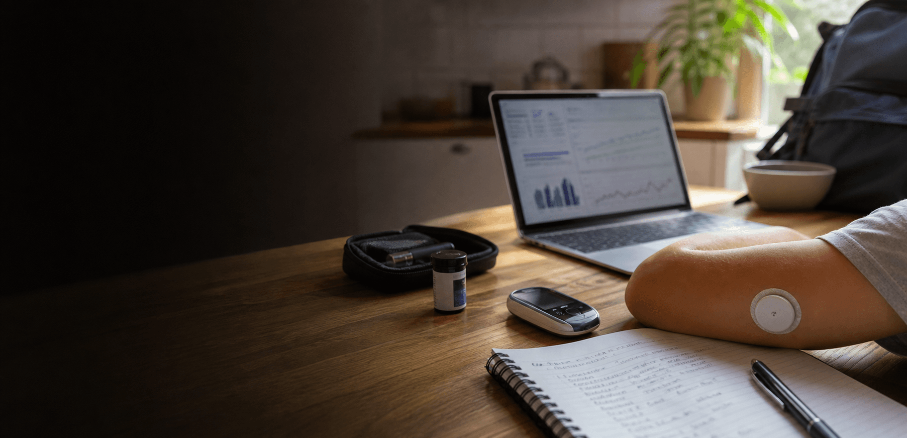 A Type 1 diabetes command-center workspace with glucose supplies, a laptop, and a CGM.
