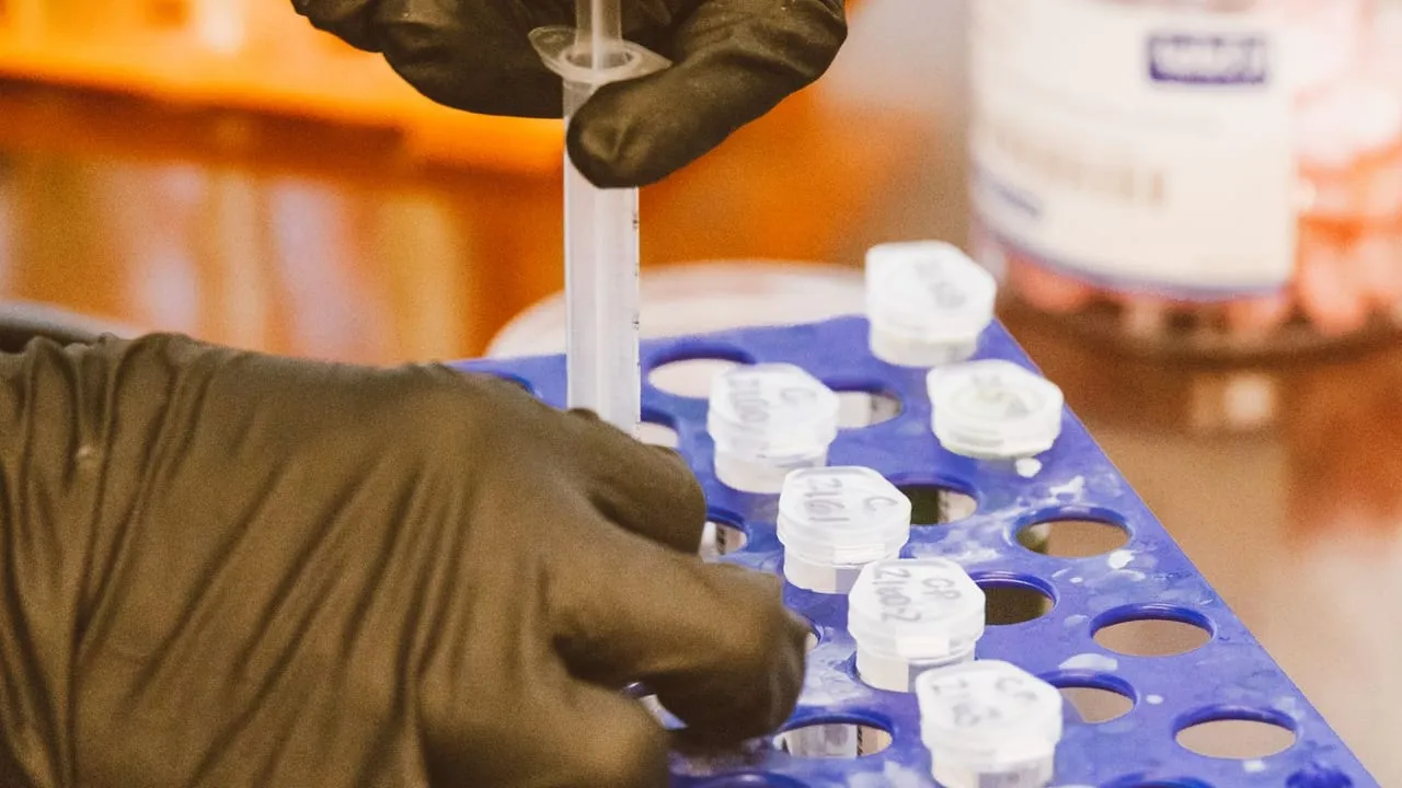 Close-up of gloved hands using syringe for precise work in a lab setting.