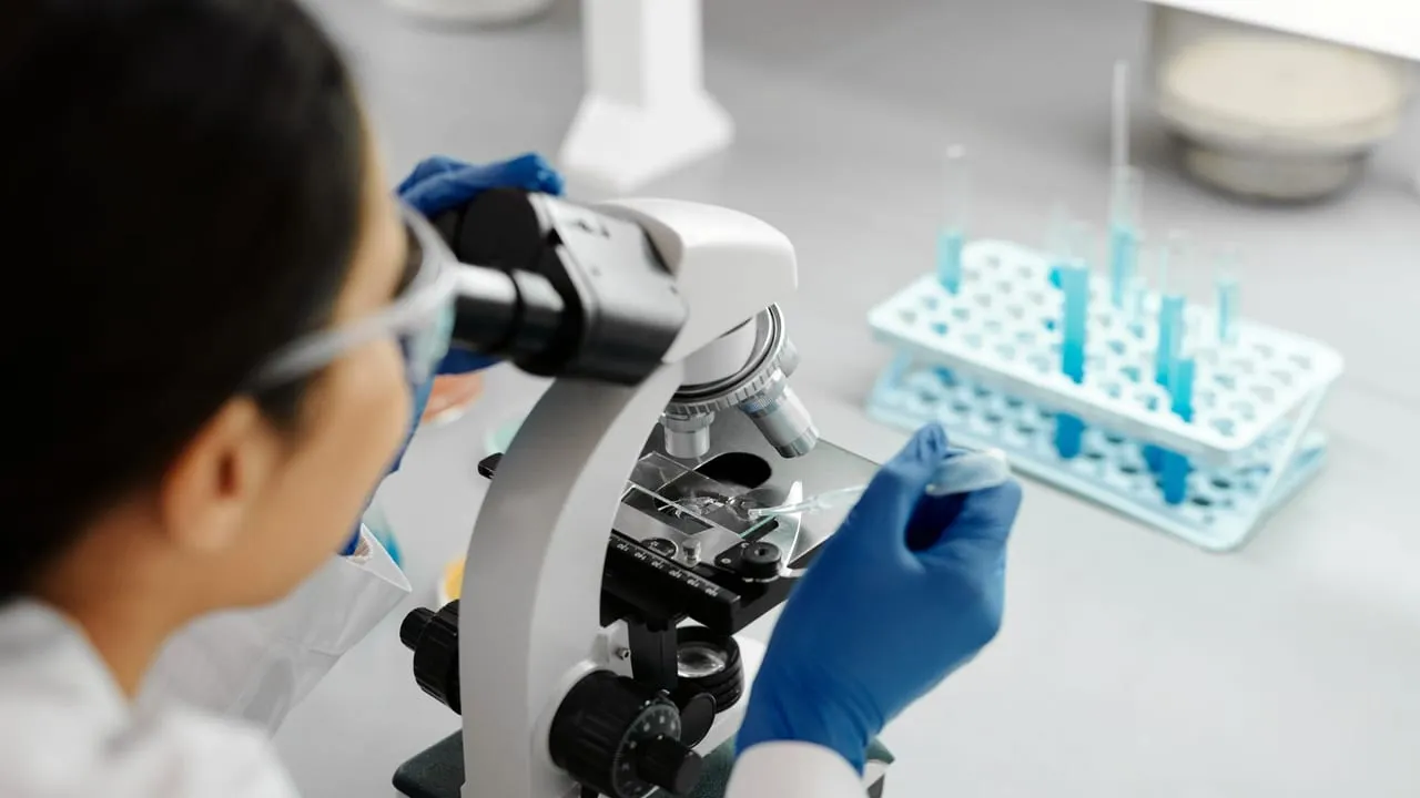 Scientist conducting research in a lab using a microscope and dropper.