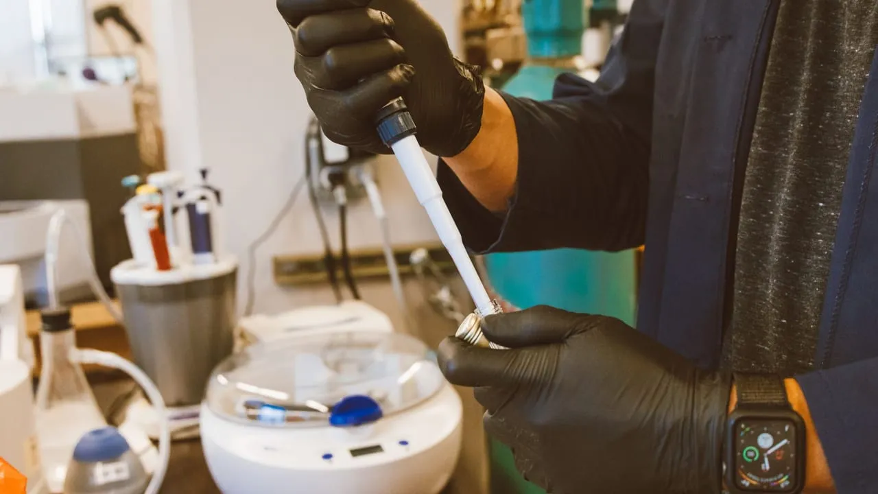 A lab technician performing an experiment with a pipette in a modern laboratory setting.