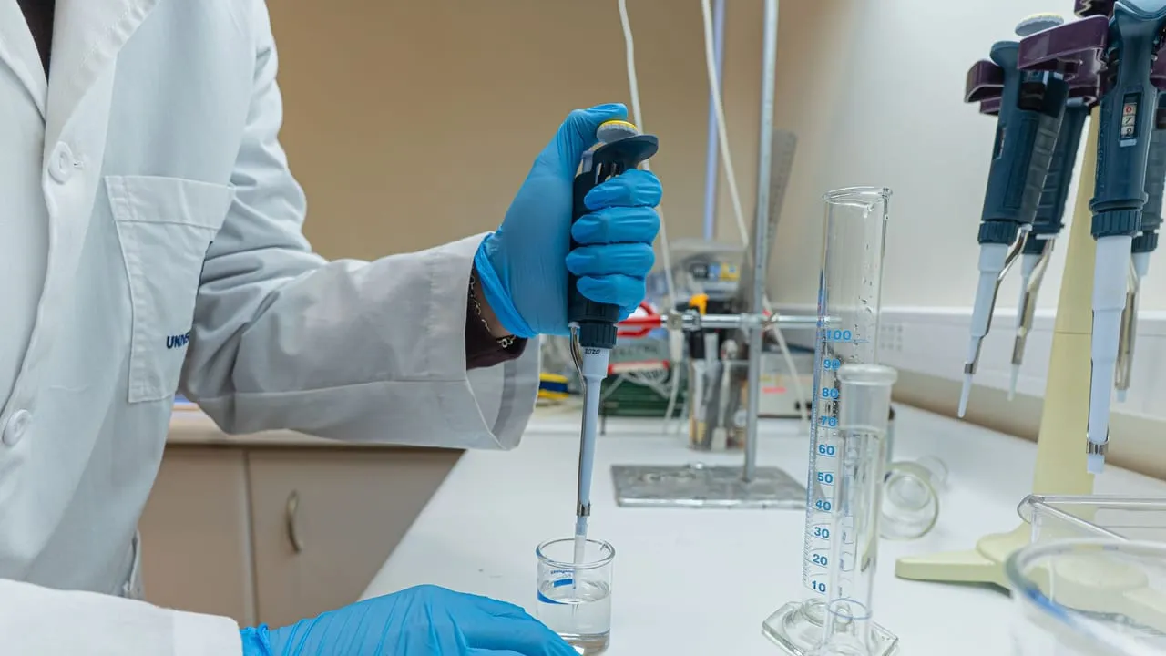 Lab scientist using pipette in chemical experiment with precision.
