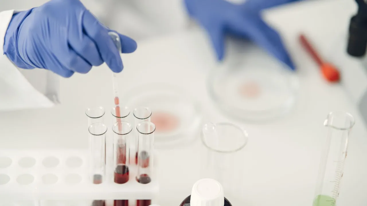 A scientist using pipette for chemical analysis in a laboratory with test tubes and protective gloves.