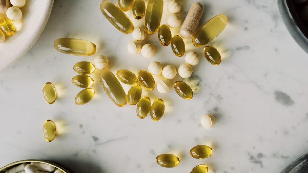 Top view of various vitamins in gelatin shell arranged on marble tabletop between different plates with drugs during photo shoot