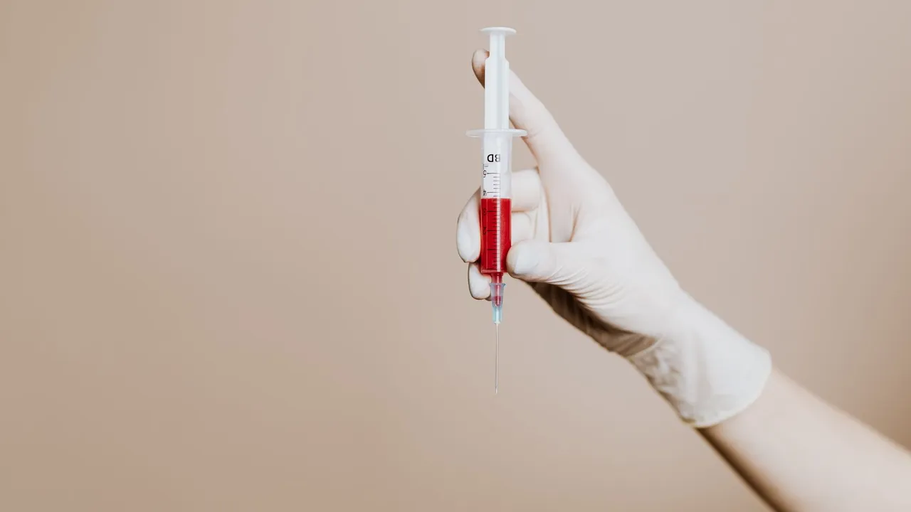 A gloved hand holding a syringe filled with red liquid, representing medical treatment or vaccination.