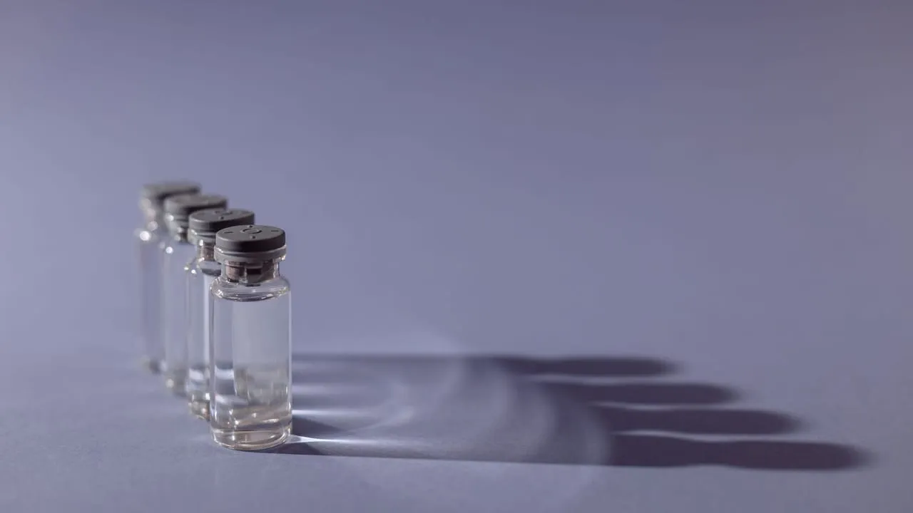 Close-up of lined up vaccine vials casting shadows, symbolizing medical advancements and health.