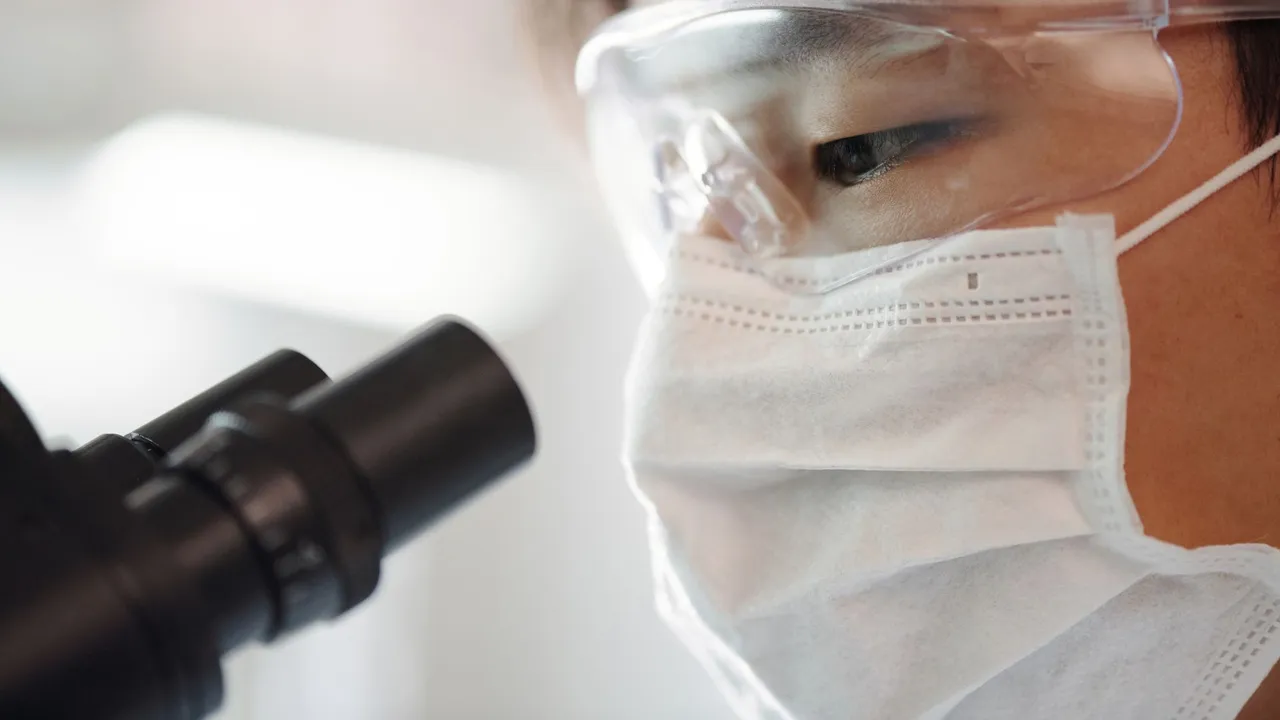 Scientist working with a microscope in a modern laboratory setup.
