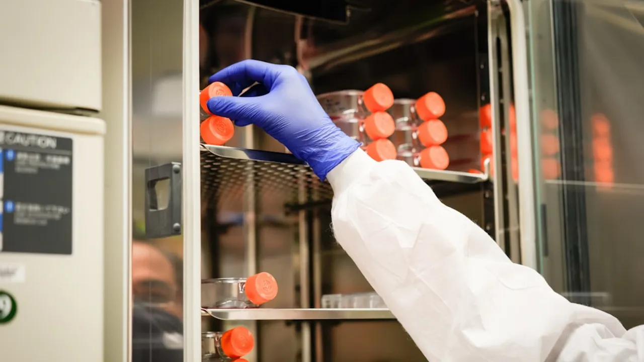 a person in a white coat and blue gloves