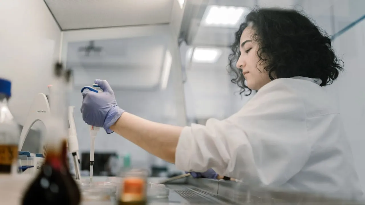 Woman in lab coat conducting research with pipette in modern laboratory.