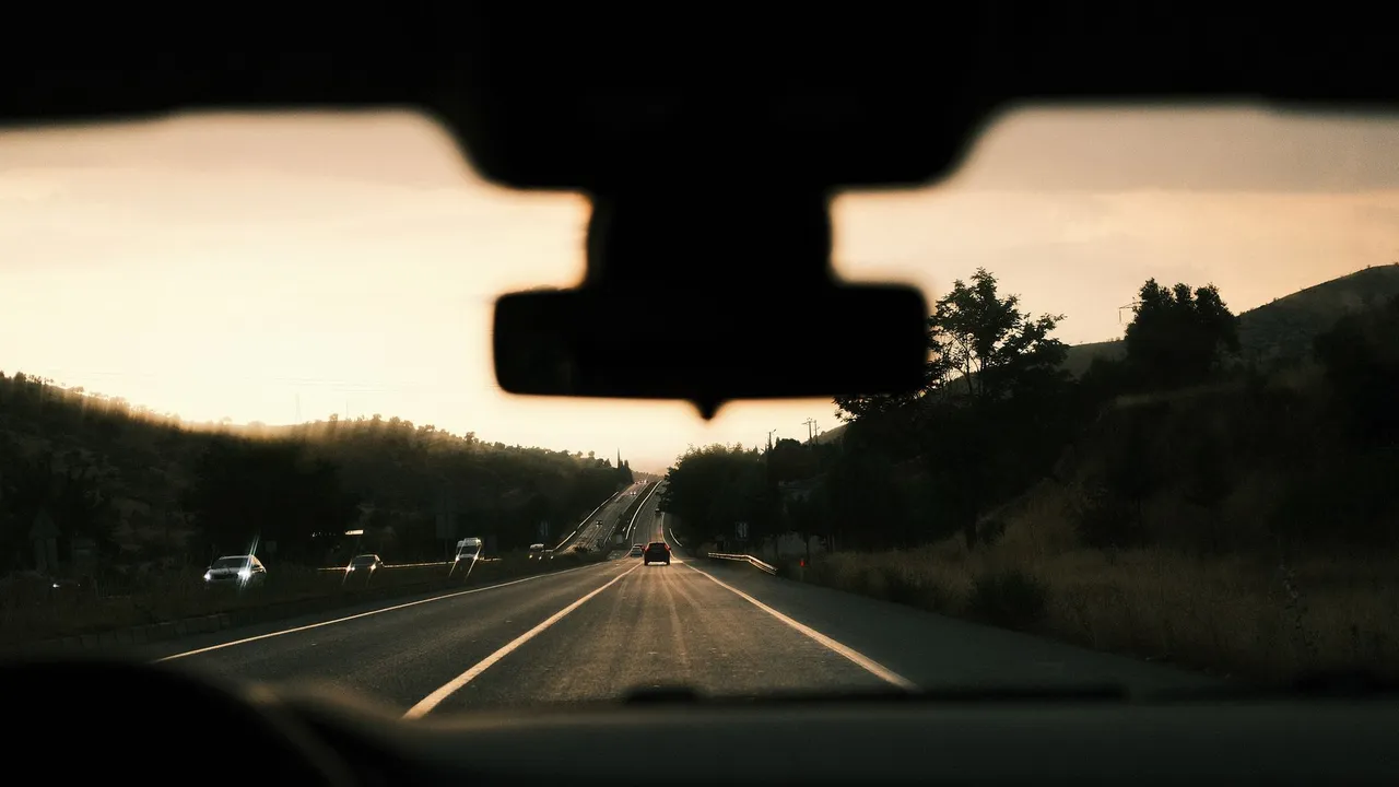 View through a car windshield of a scenic highway during sunset, capturing the road trip vibe.