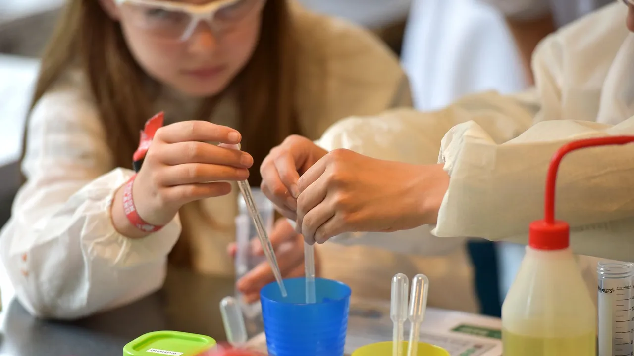 Children conducting science experiments with pipettes and safety glasses in a lab setting.