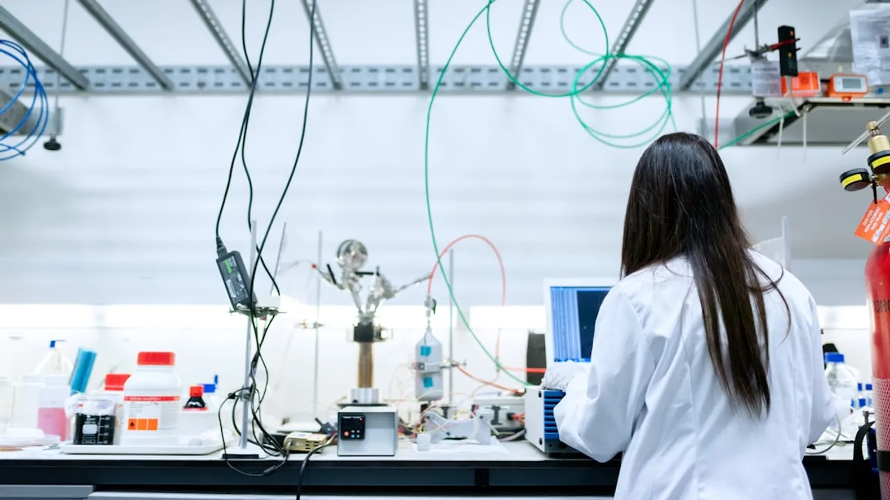 A scientist in a white lab coat using a laptop in a laboratory