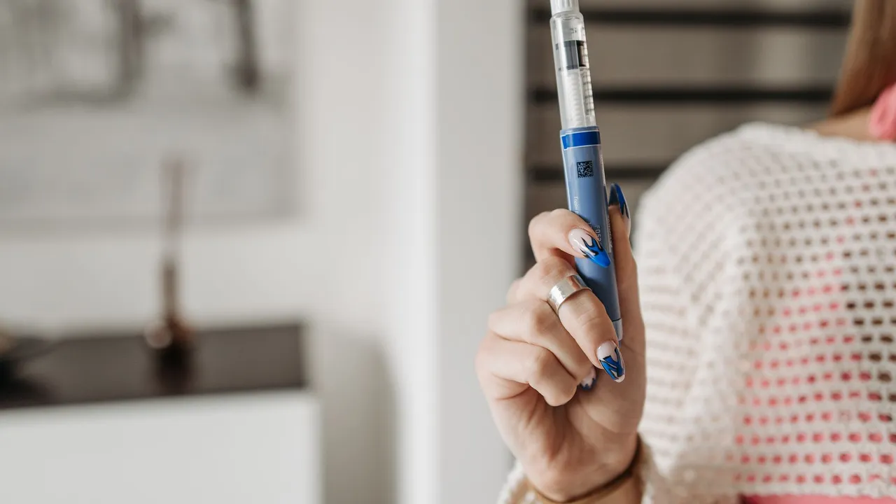 Woman holding an insulin pen, showcasing healthcare and diabetes management in a modern setting.