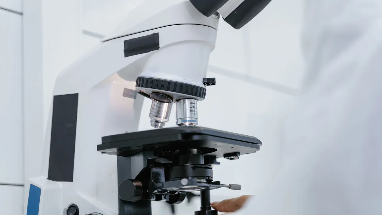 Detailed view of a scientist operating a microscope in a laboratory setting.