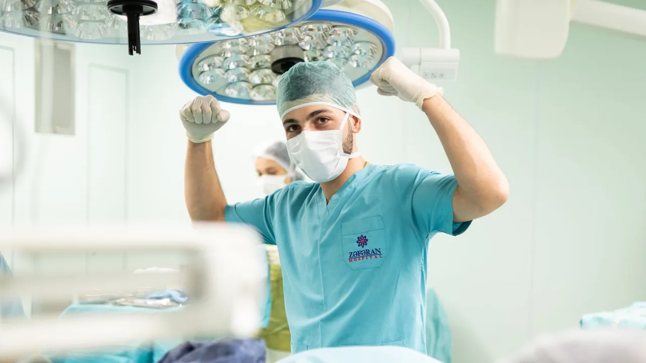 A surgeon in scrubs celebrates after a successful surgery in an operating room.