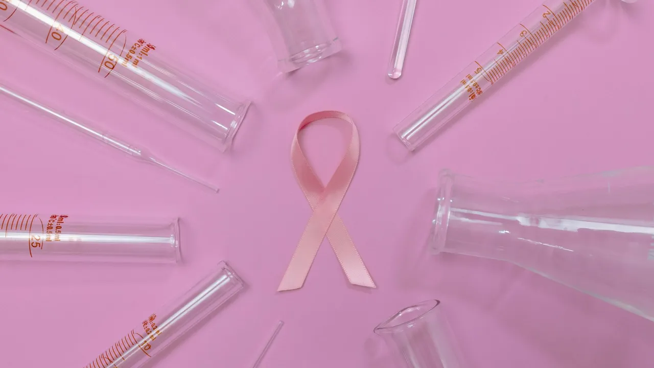 A pink ribbon surrounded by laboratory glassware symbolizes breast cancer research and awareness.