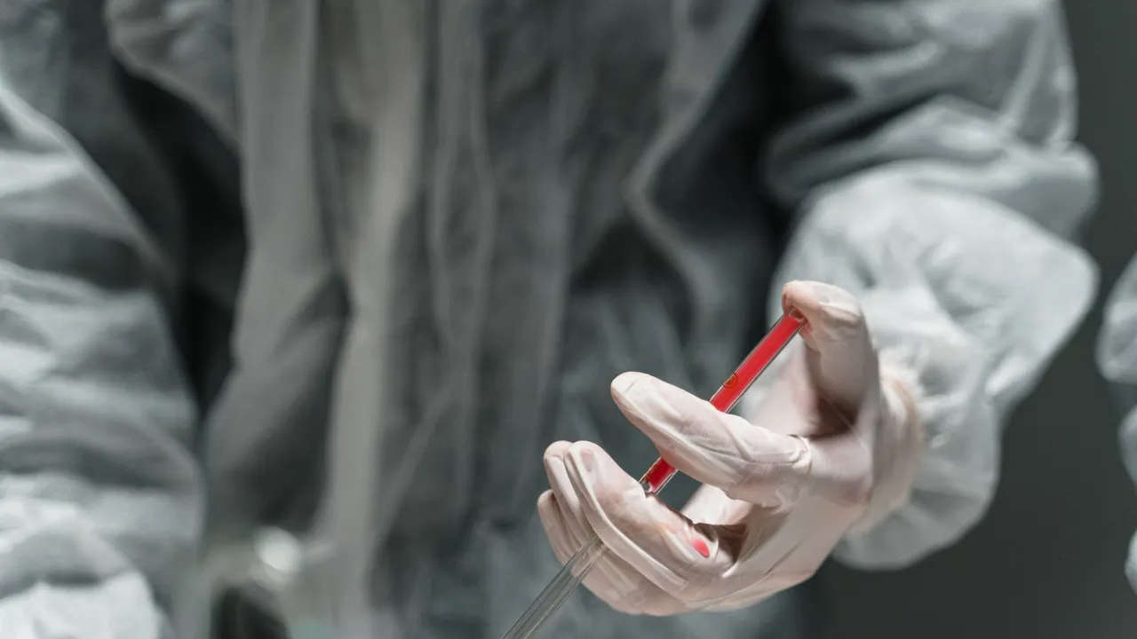 Scientist in protective gear handling a syringe in a laboratory setting.