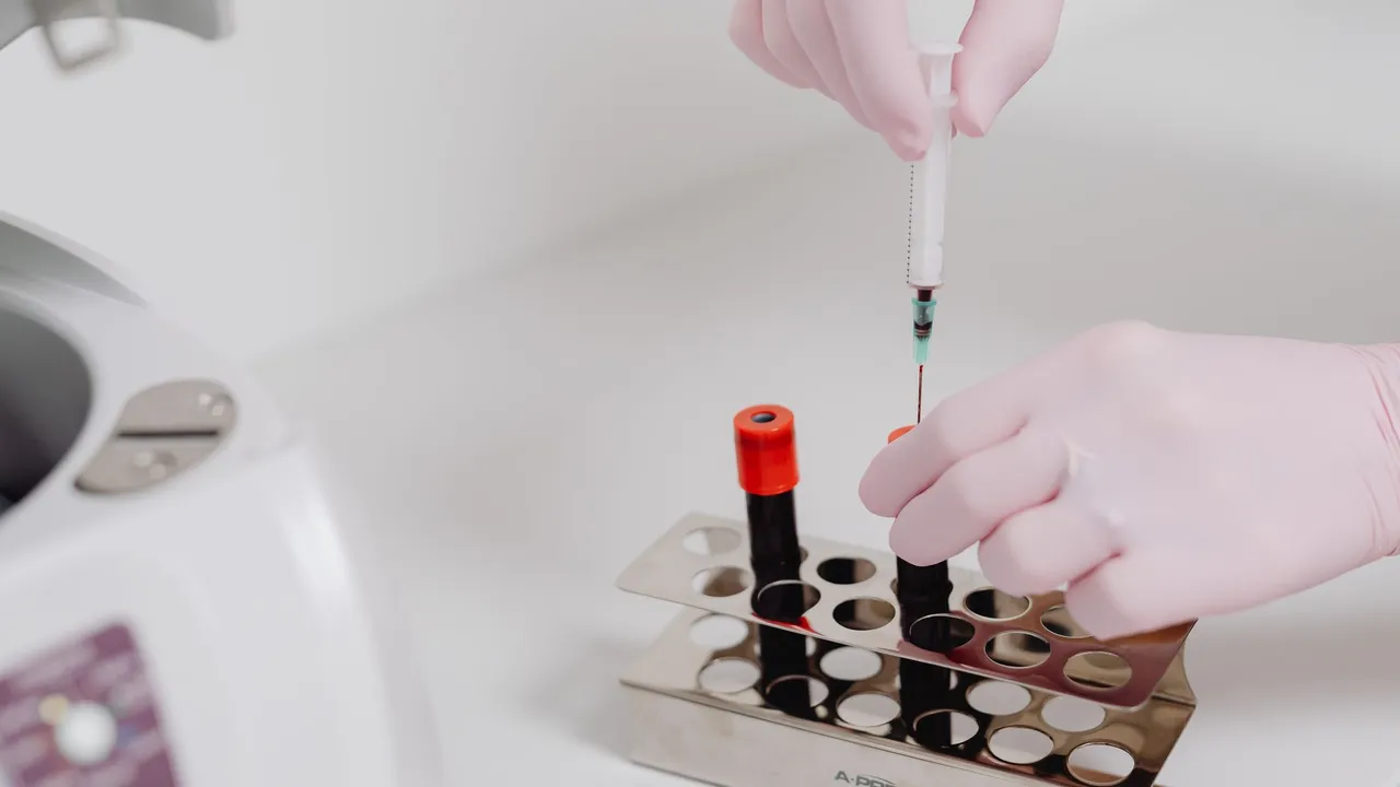 Close-up of lab technician's hands with gloves handling blood samples.
