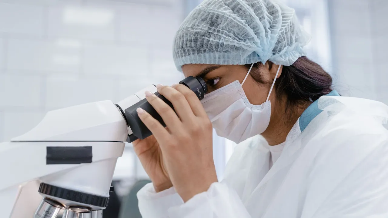 A female scientist uses a microscope in a laboratory, focusing on research and analysis.