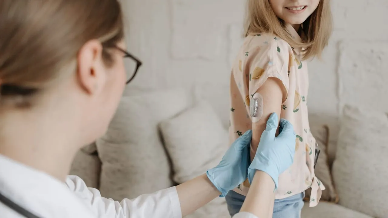 A young girl receives an insulin checkup from a medical professional at home, managing diabetes.