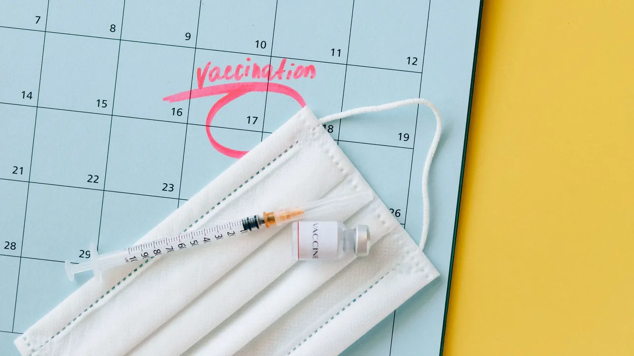 Close-up of a calendar marked for vaccination, with a syringe and face mask highlighting healthcare theme.