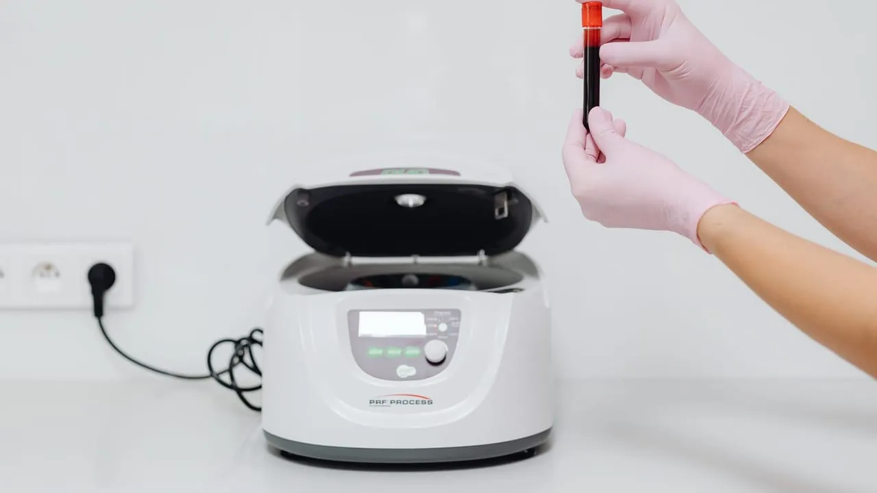 Medical professional handling blood sample in a centrifuge for laboratory testing.