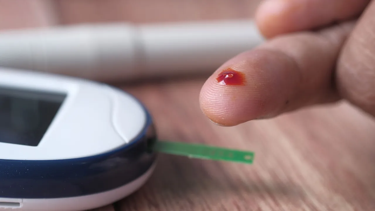 A close-up of a finger prick and blood glucose monitor for diabetes testing.