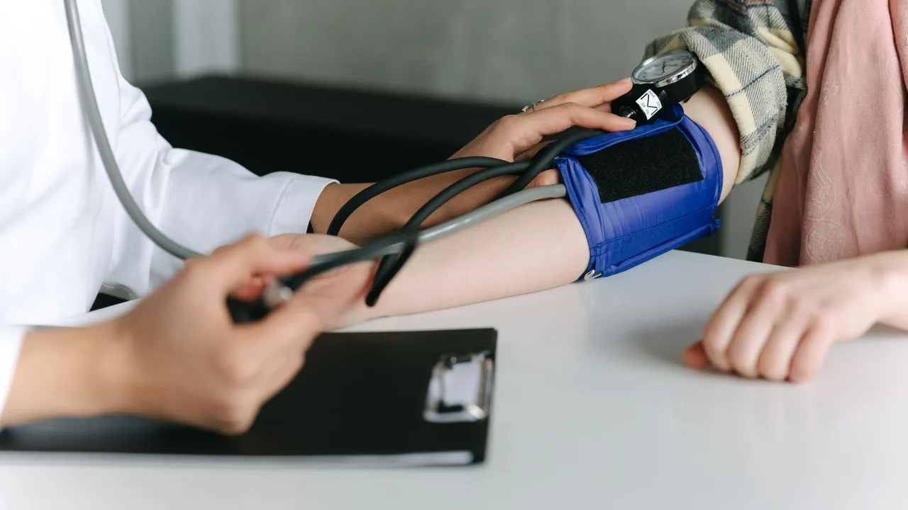 A healthcare worker uses a sphygmomanometer to check a patient's blood pressure in a medical office.