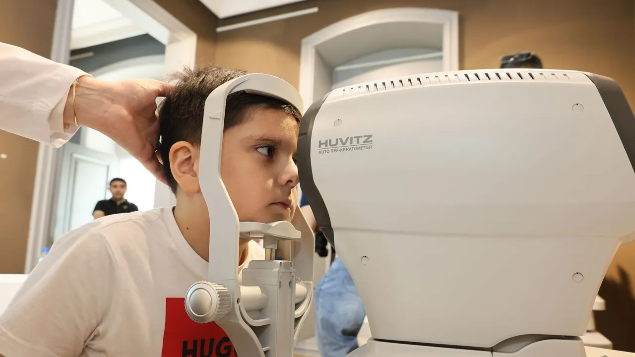 Young boy receiving an eye exam using autorefractor at a clinic. Healthcare concept.