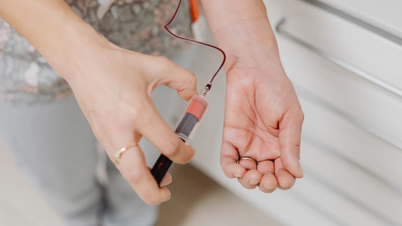 A close-up view of a blood draw procedure with syringe and vial, focusing on healthcare treatment.