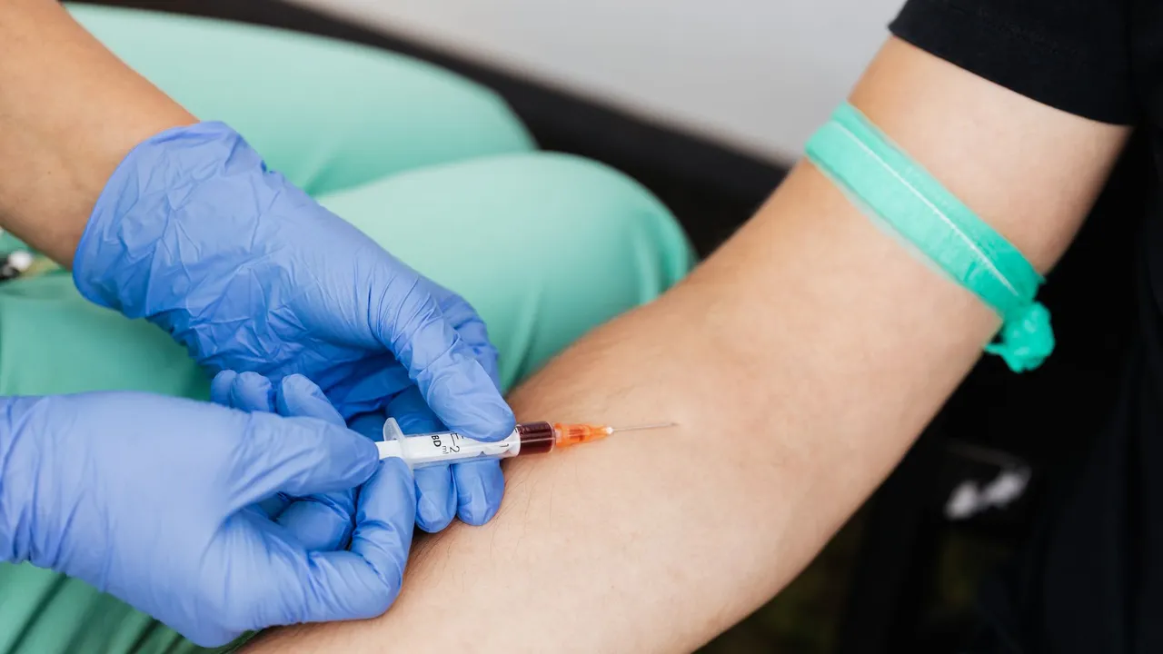 Healthcare worker drawing blood from patient's arm with syringe.