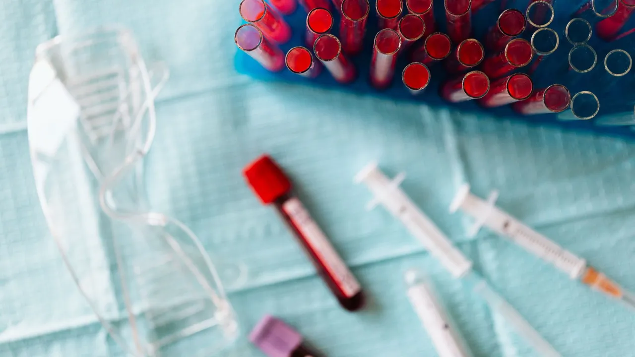 Top view of empty and full glass test tubes of blood placed on plastic container near syringes and empty and full glass vials of blood and plastic eyeglasses fo