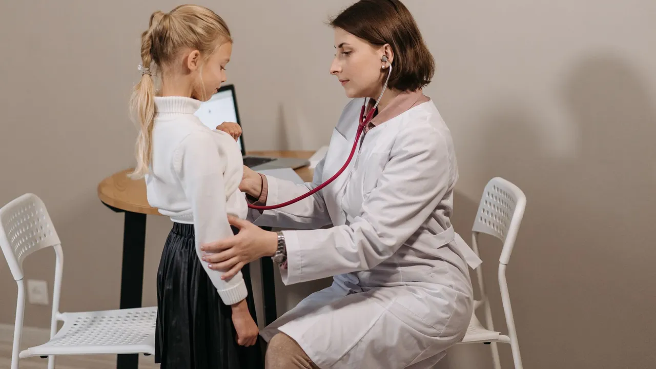 A pediatrician listens to a child's heartbeat during a check-up in a clinic setting.