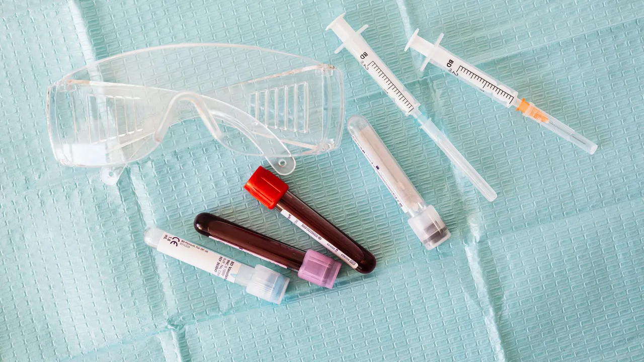 Top view of empty and full of blood vials and plastic syringes and eyeglasses  placed on medical diaper