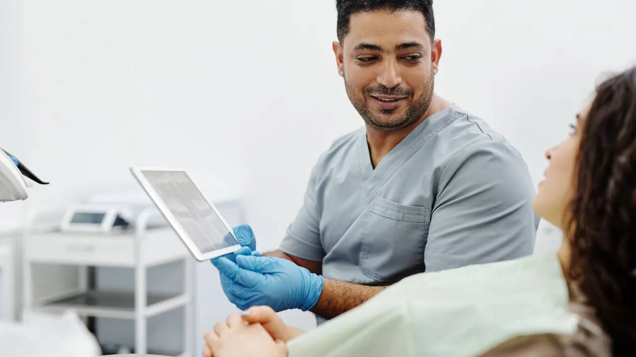 Nurse uses digital tablet for patient consultation and diagnosis in a clinical setting.