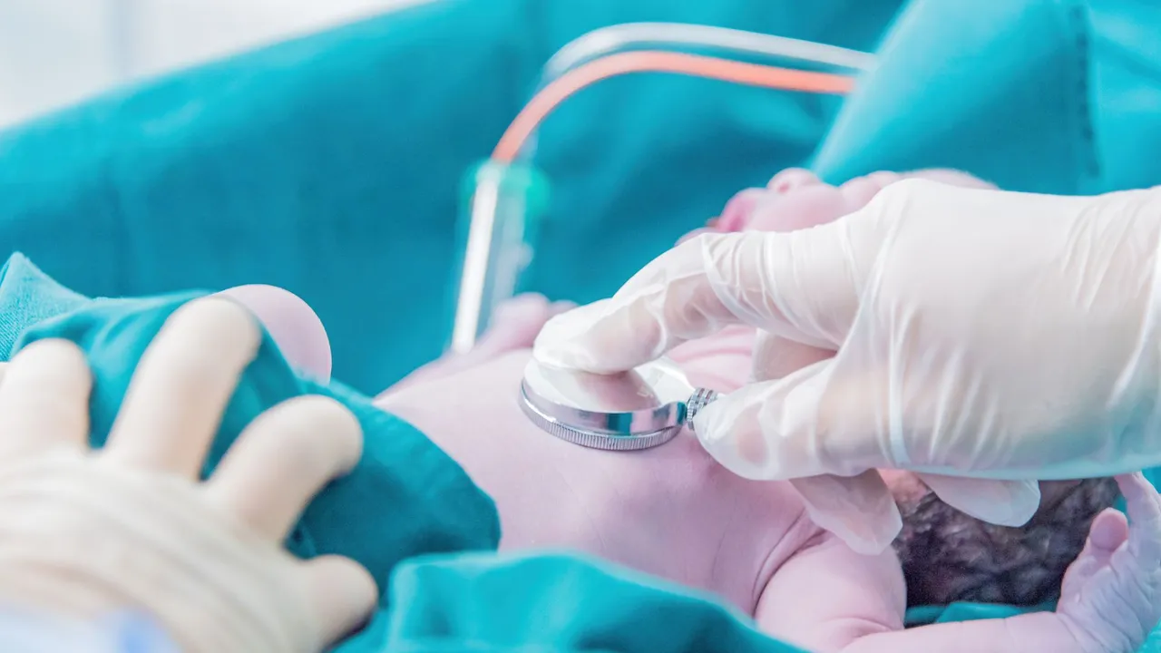 Medical professional examining a newborn baby with a stethoscope in a hospital setting.