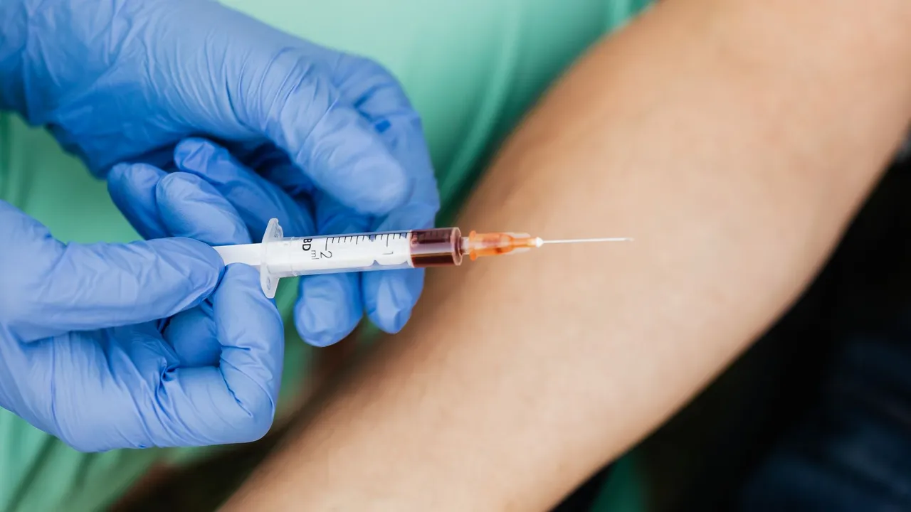 Medical professional using syringe for blood extraction with latex gloves.