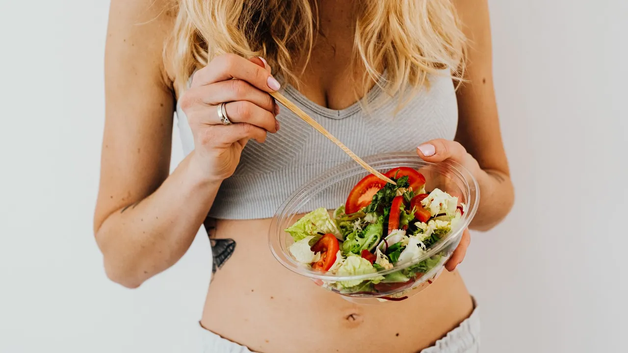 Woman in sports attire enjoys a fresh, nutritious salad, embodying a healthy lifestyle.