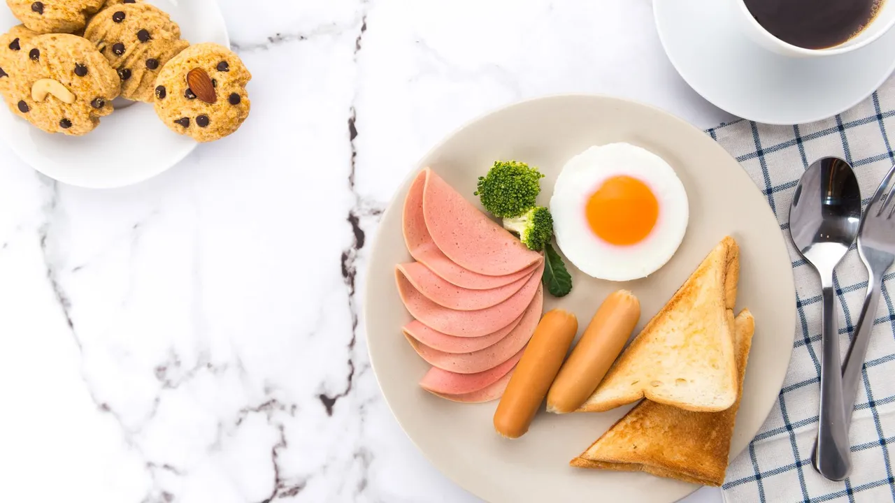 An appetizing breakfast spread featuring eggs, sausages, toast, and coffee on a marble surface.