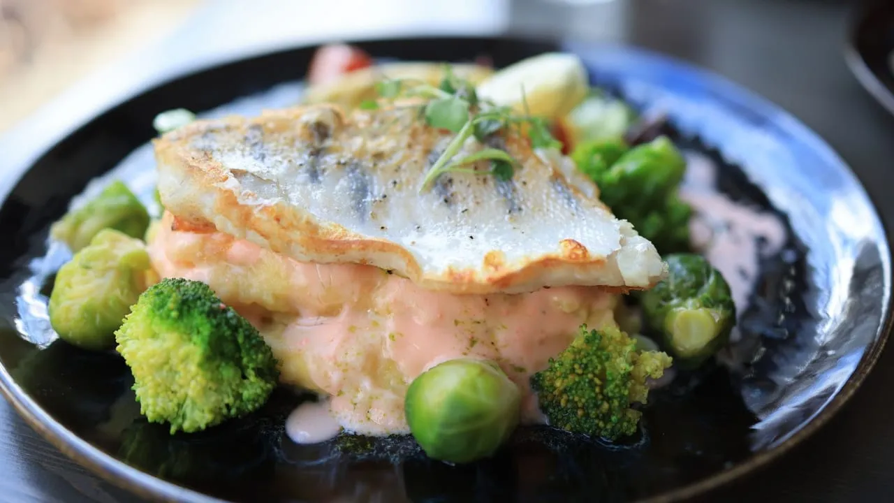 Delicious fish fillet served with broccoli, Brussels sprouts, and creamy sauce.