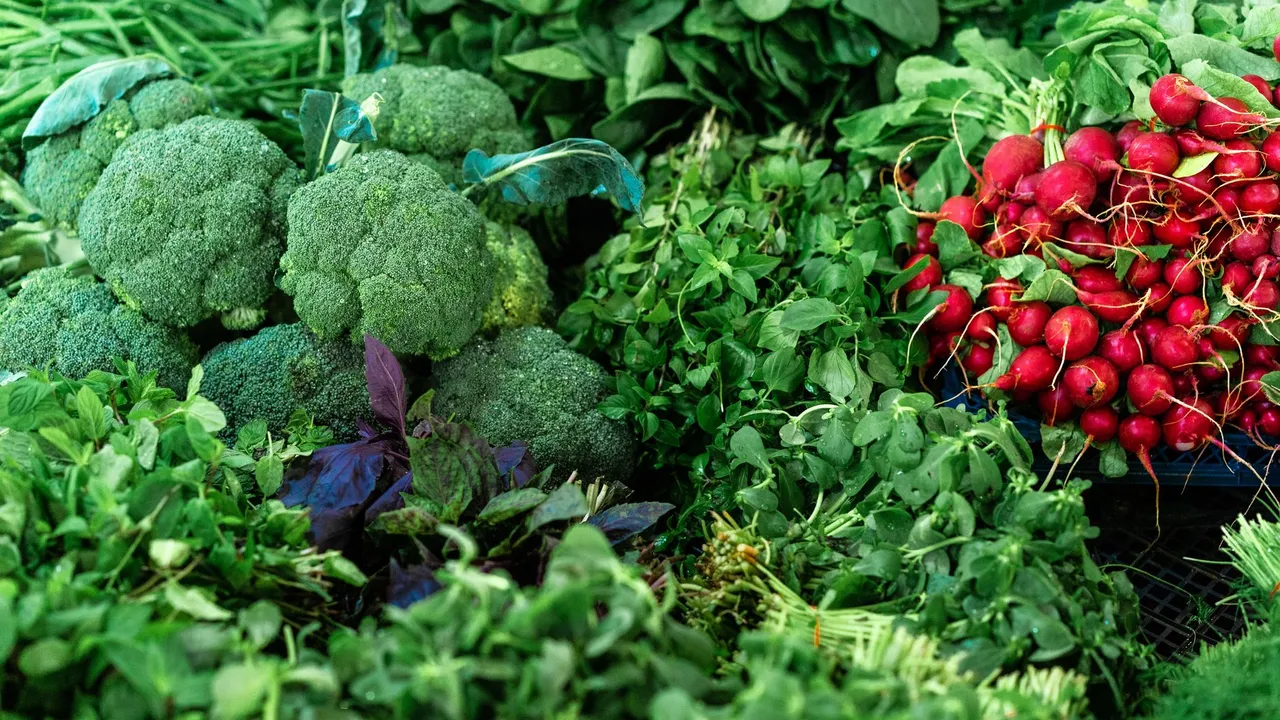 A vibrant assortment of fresh broccoli, radishes, and leafy greens at a market, ideal for healthy eating.
