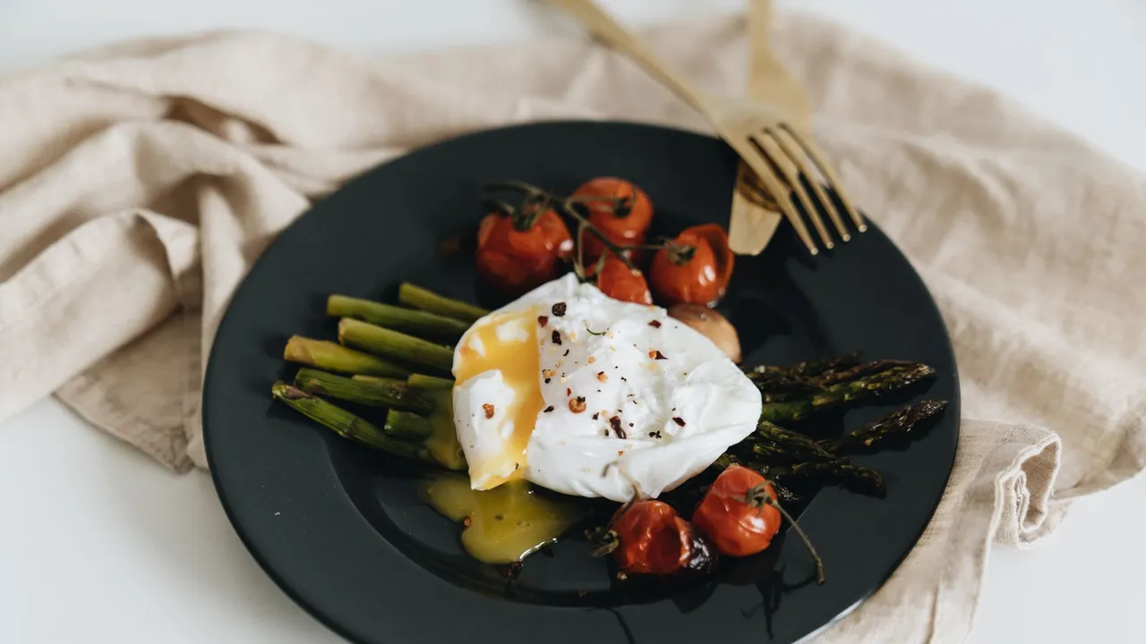 Tasty poached egg served with asparagus and cherry tomatoes, perfect for a healthy meal.