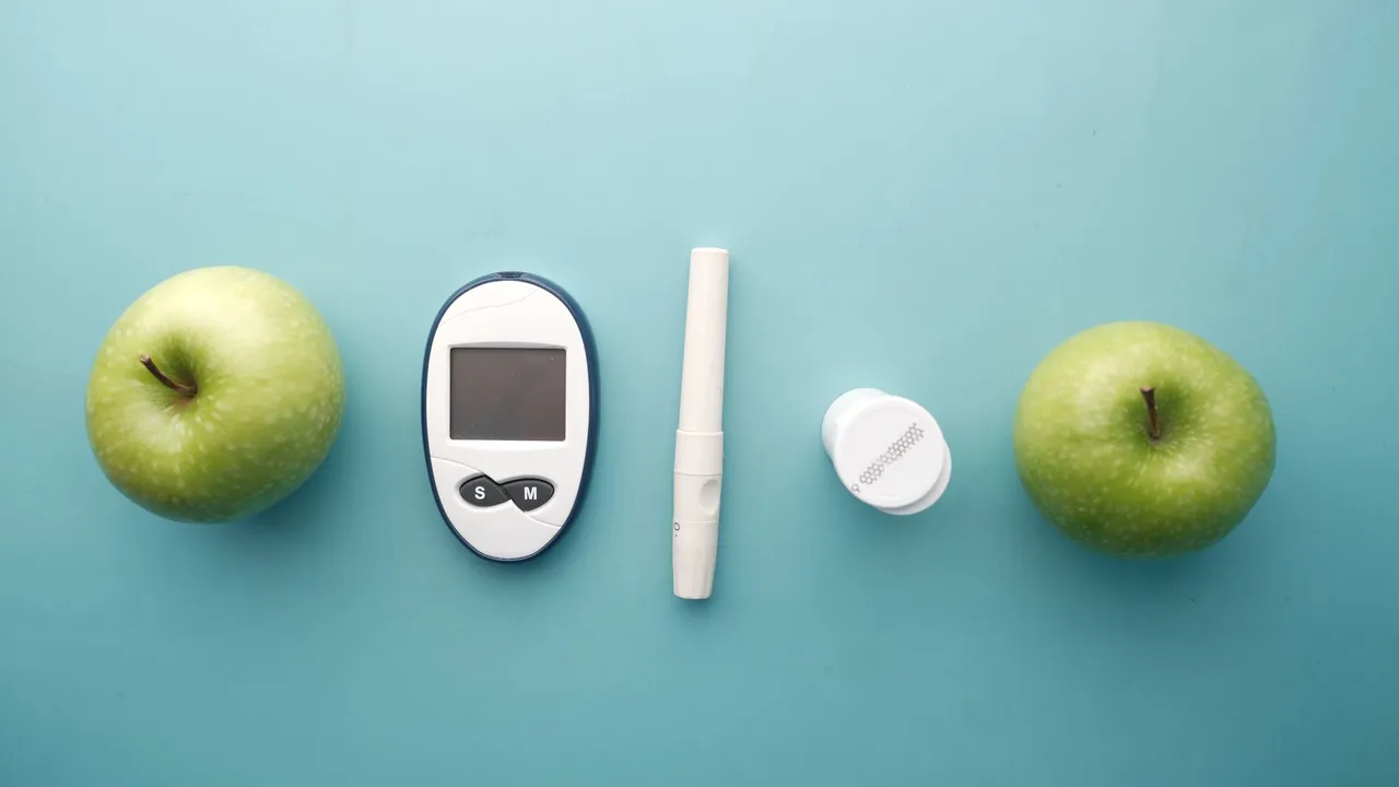 A diabetes testing kit alongside green apples on a blue background, symbolizing health and diet management.