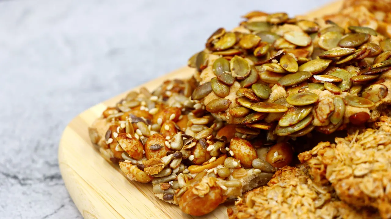 Close-up of various healthy homemade mixed nut and seed snacks on a wooden board.