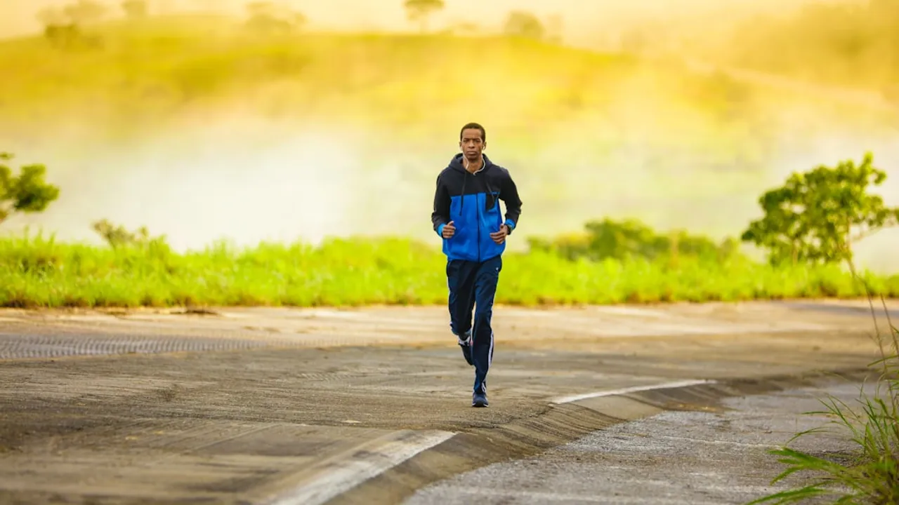 man in track suit jogging on concrete road