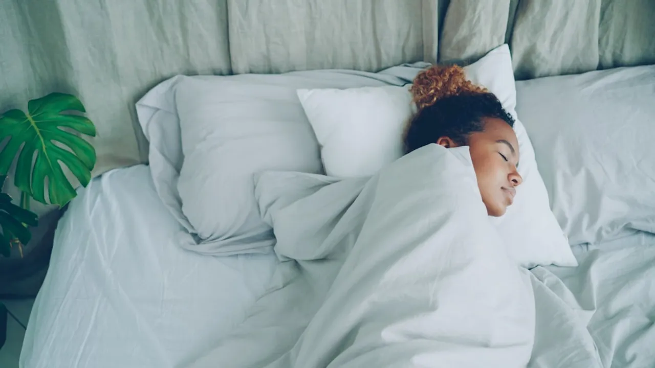 A young woman sleeping peacefully in a white bed.