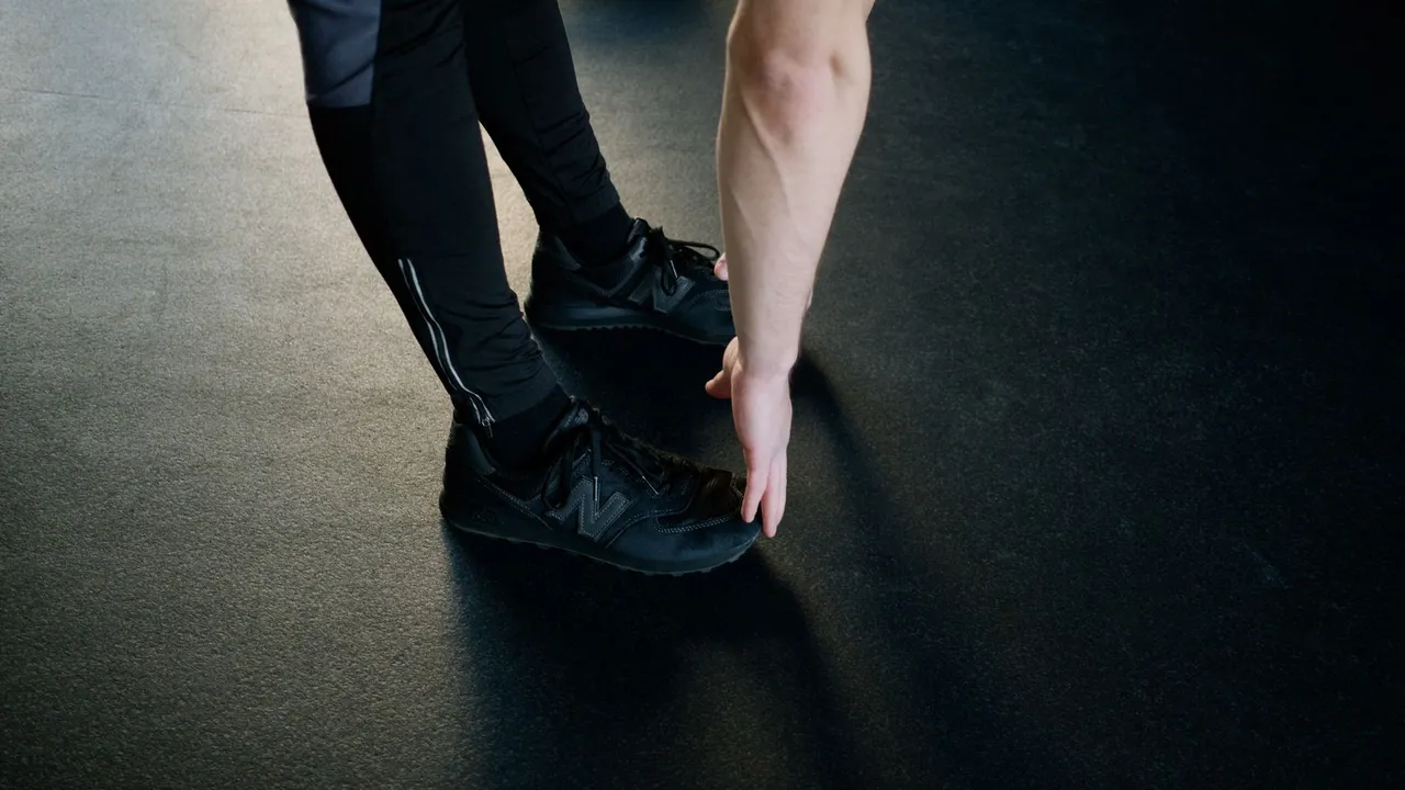A person stretching in a gym, reaching down to touch their feet. Fitness and exercise concept.