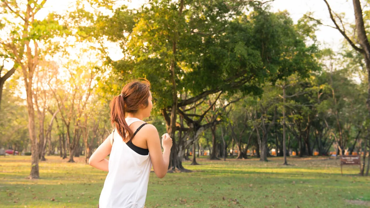 A woman jogging through a forest park in the early morning sunshine, enjoying a healthy lifestyle.