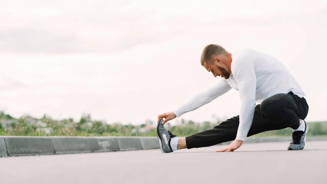 Adult male stretching outdoors, focusing on fitness and healthy lifestyle in a casual sportswear outfit.