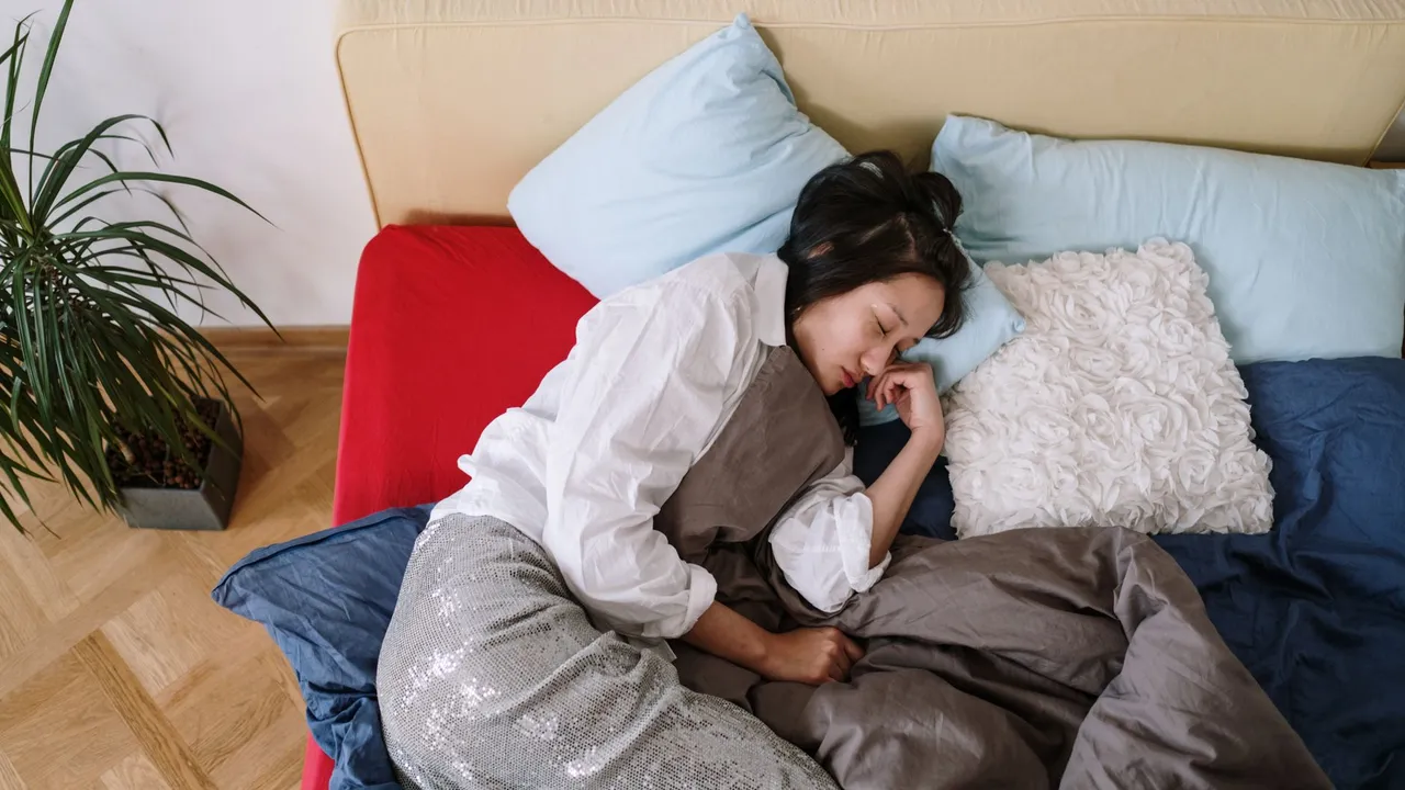 A woman sleeps comfortably on a bed surrounded by pillows and blankets, capturing a serene and restful moment.