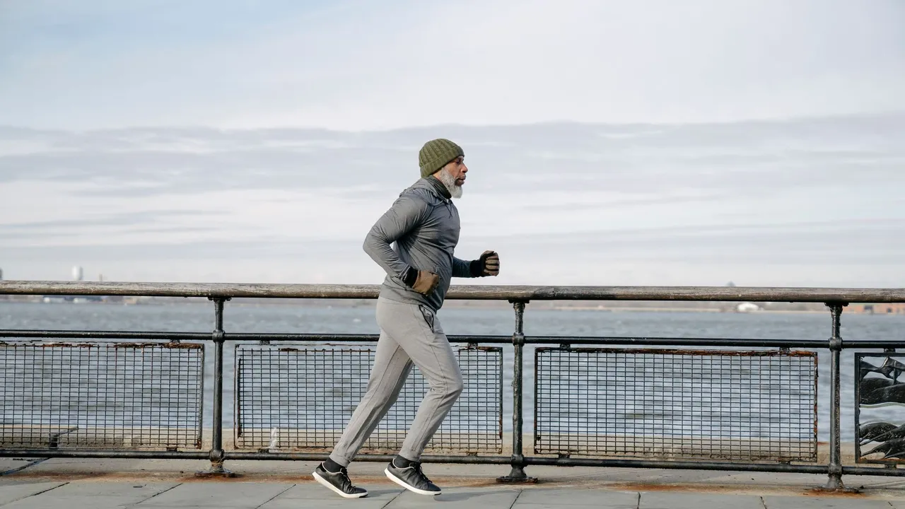 Elderly man running along waterfront, embracing a healthy lifestyle and exercise routine.